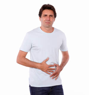 Middle aged man wearing a white t-shirt with his hands on his stomach in pain 