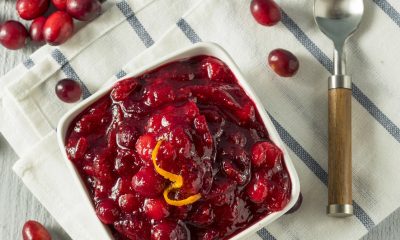 white bowl of bright burgundy cranberry sauce topped with orange zest